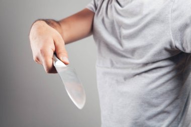 Adam gri arka planda bir bıçakla tehdit ediyor.