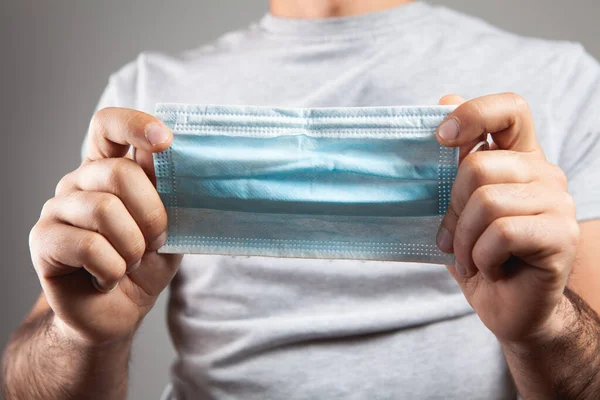 Man Met Een Medisch Masker Zijn Hand Een Grijze Achtergrond — Stockfoto