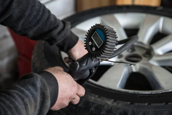 점에서 일하는 동안의 타이어의 압력을 검사한다 — 스톡 사진
