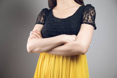 Elbise içinde kollarını kavuşturdu.