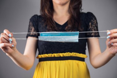 Elinde maske tutan genç bir kadın.