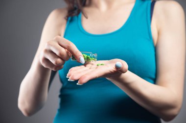 Elinde bir kavanoz hap tutan genç bir kadın.