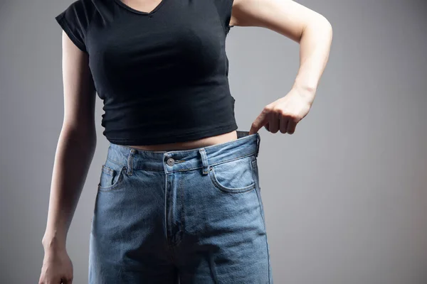 Young Girl Pulls Jeans Gray Background — Stock Photo, Image