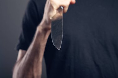 Adam gri arka planda bir bıçakla tehdit ediyor.