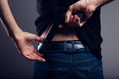 Bir adam arkadan silah çeker.