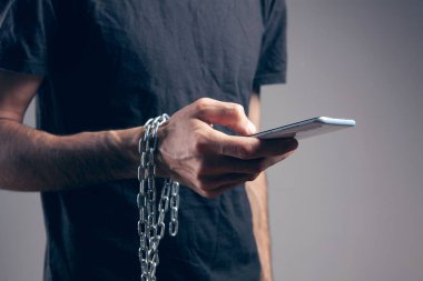 Zincirli bir adam elinde telefon tutuyor.
