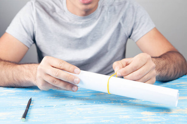 papers are wrapped in a roll. man holding sitting in front of the table