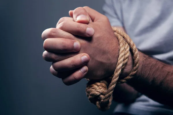 the man\'s hands are tied with a rope