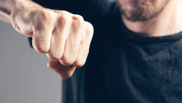 Adam gri arka planda yumruğunu gösteriyor
