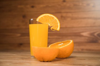 Tahta bir masada portakal ve bardakta içki.