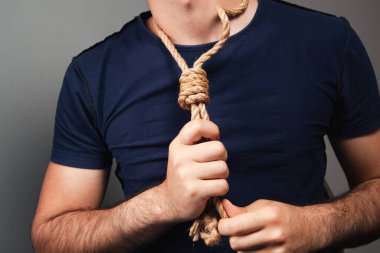 Adam ilmeği boynuna geçirir. Gri arkaplanda intihar kavramı