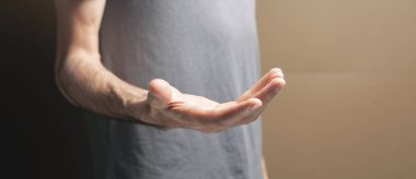Adam kahverengi arkaplanda boş avuçlar gösterir