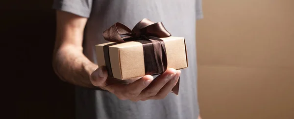 man holding gift box on brown background