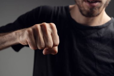 Adam gri arka planda yumruğunu gösteriyor