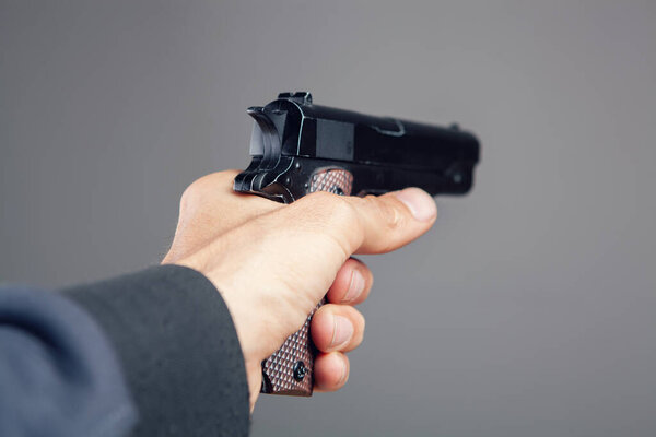 hand holding pistol on gray background