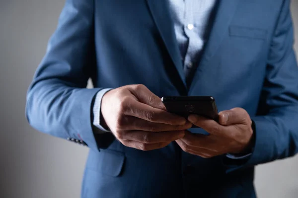 a man in a suit stands with a phone