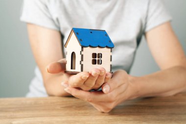 Elinde ev tutan genç bir kadın.