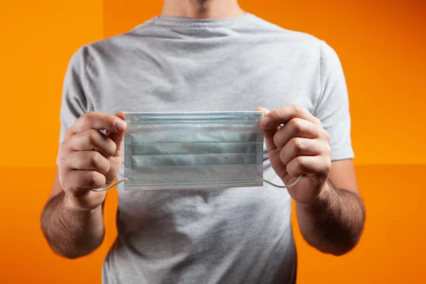 Met Een Masker Zijn Handen Een Oranje Achtergrond — Stockfoto