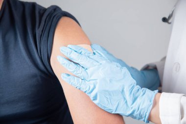 Bir doktor genç bir adama aşı yapar.