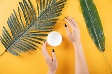 Masaya portakal rengi yapraklarla el kremi süren genç bir kadın.