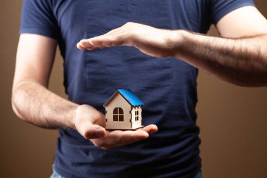 Kahverengi arka planda evi tutan adam