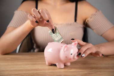 Kadın kumbaraya para atıyor.