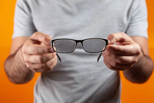 Chico Joven Sosteniendo Gafas Ópticas Sobre Fondo Naranja — Foto de Stock