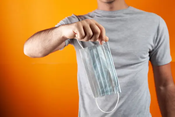 Met Een Masker Zijn Handen Een Oranje Achtergrond — Stockfoto