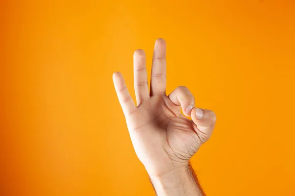 手はオレンジの背景でOkを示す — ストック写真
