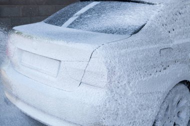 Yüksek basınçlı hortumu olan bir adam köpük sürer.