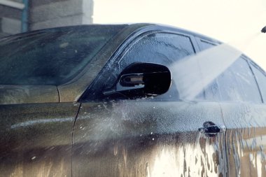 Bir adam arabasını suyla yıkar.