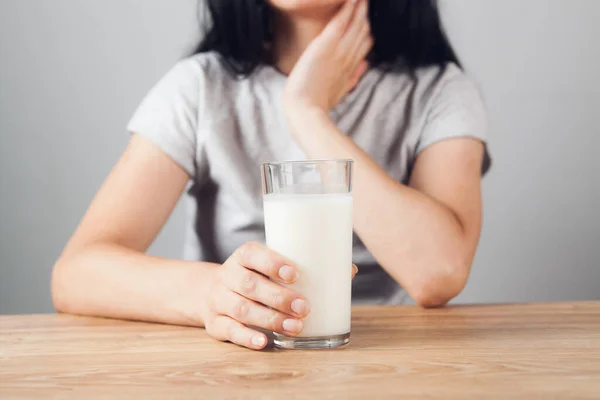 坐在桌旁的女孩端着一杯牛奶 — 图库照片