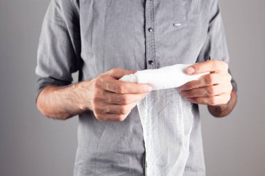 Gri arka planda bandaj tutan bir adam.