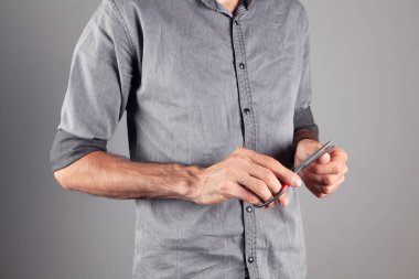 Adam tırnaklarını makasla kesiyor.