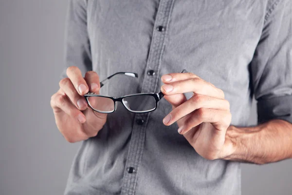 Gri Arka Planda Optik Gözlük Tutan Genç Adam — Stok fotoğraf