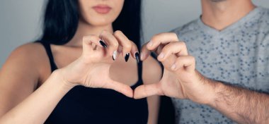 Erkek ve kadın elleriyle yüreklerini gösterirler.