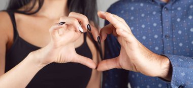 Erkek ve kadın elleriyle yüreklerini gösterirler.