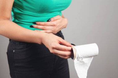 Kadın tuvalet kağıdı ve mide ağrısıyla ayakta duruyor.
