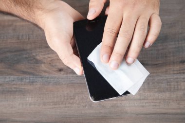Telefonu peçeteyle siler.