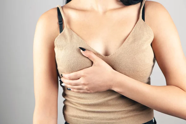 a young woman has a chest pain on a gray background