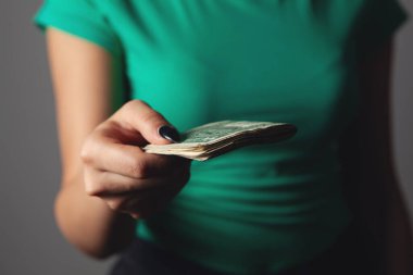 Kadın gri arka planda para sayıyor.