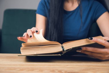 Masanın önünde kitap okuyan bir kız.