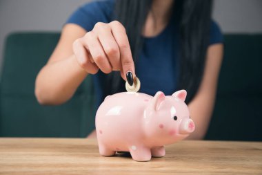 Kadın domuz kumbarasına bozuk para atıyor.