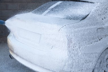 Bir adam arabasını suyla yıkar.