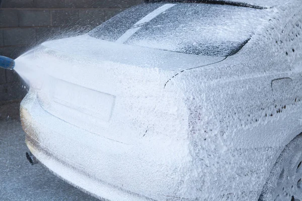 Bir adam arabasını suyla yıkar.