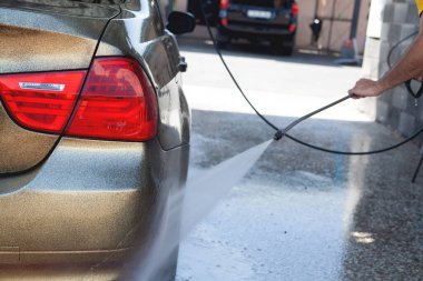 Bir adam arabasını suyla yıkar.