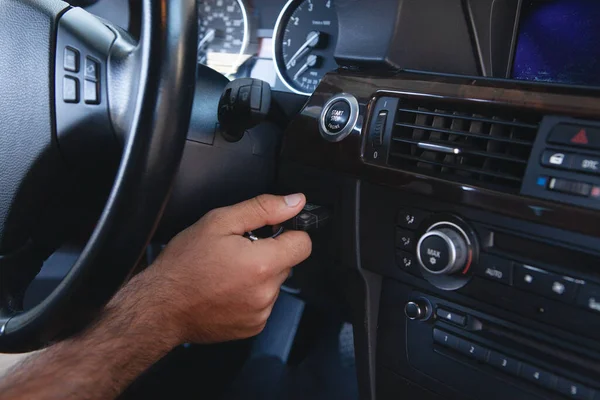 a man presses the start button in the car