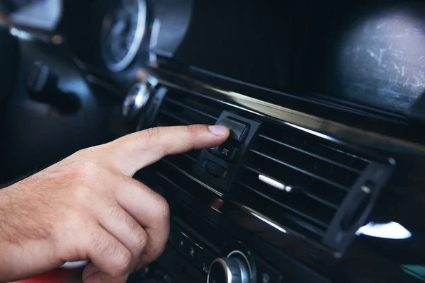 a man presses the start button in the car