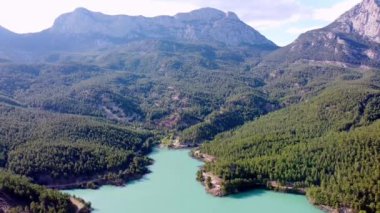 Zümrüt bir dağ gölünün üzerinden uçarak dağlar ve eko-çiftlikte organik ürünlerin yetiştiği seraların üzerinden geçen bir dağ nehri.