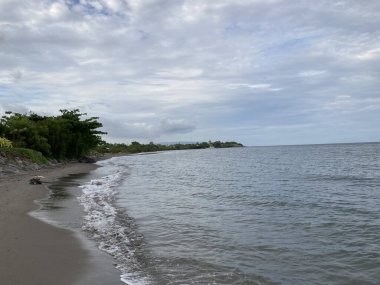 Denizin kumlu sahilinde küçük sıcak dalgalar yavaşça kıyıya vurur. Yüksek kalite fotoğraf